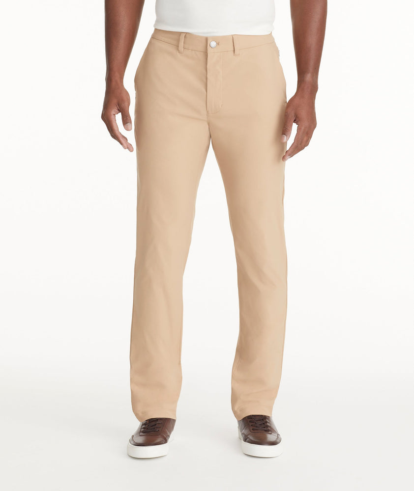 Model is wearing UNTUCKit Traveler Tech Pants in Tan. 