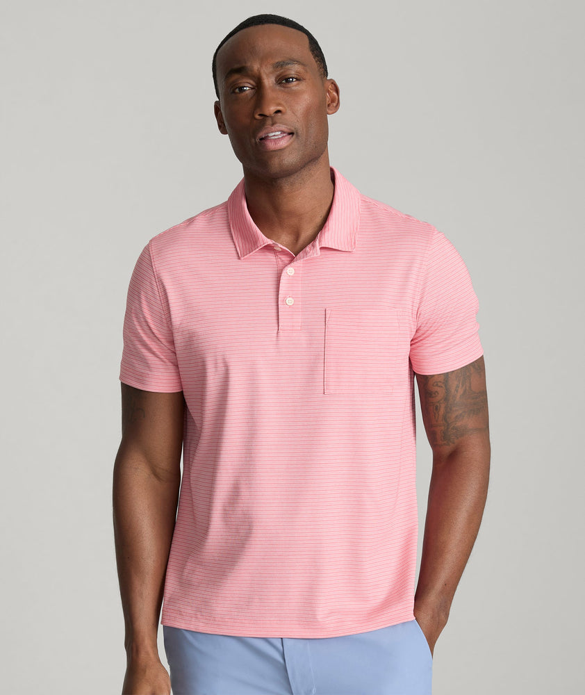 Model is wearing UNTUCKit Gilbert Striped Performance Polo in Rose of Sharon.