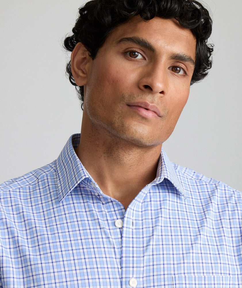 Model is wearing UNTUCKit Kaleb long sleeve performance shirt in light blue and white check. 