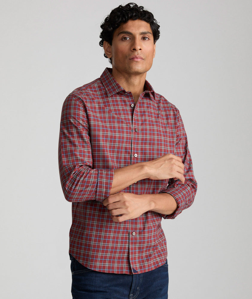 Model is wearing UNTUCKit Lynch shirt in burnt red and navy check. 