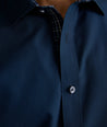 Model is wearing UNTUCKit Roberts wrinkle-free shirt in solid navy with blue check contrast cuff. 